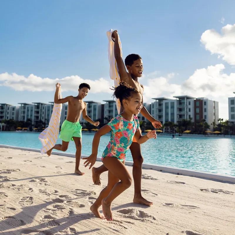 Kids Playing on the Beach by Evermore Bay An image of three kids smiling while playing on the beach by Evermore Bay at Evermore Orlando Resort.