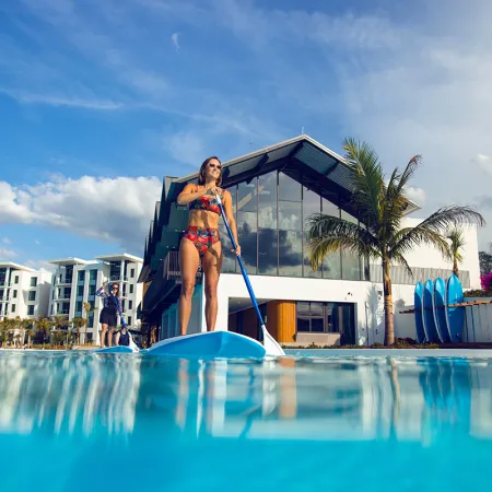 An image of two women paddleboarding in Evermore Bay at Evermore Orlando Resort.