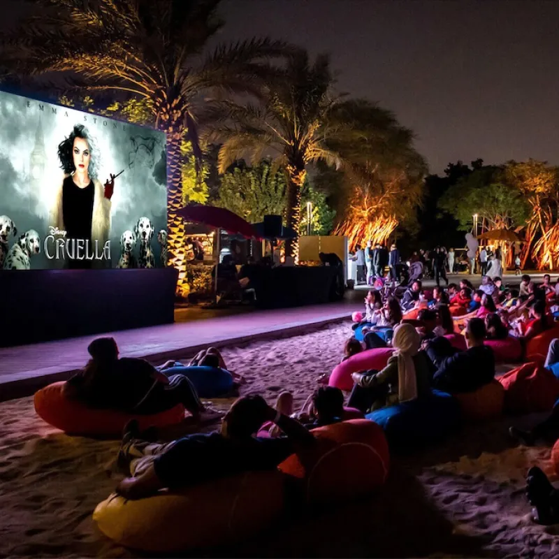 Bayside Blockbusters Guests enjoying outdoor movie on projector screen along the shores of Evermore bay