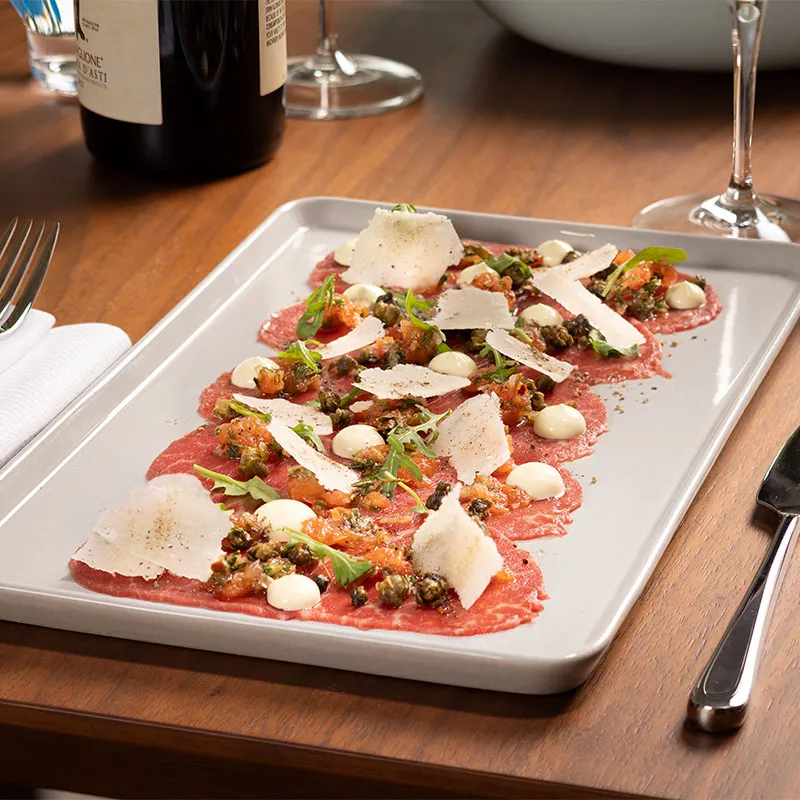 Beef Carpaccio at Sophia's Trattoria An image of the Beef Carpaccio dish on a table in Sophia's Trattoria in Conrad Orlando at Evermore Orlando Resort.