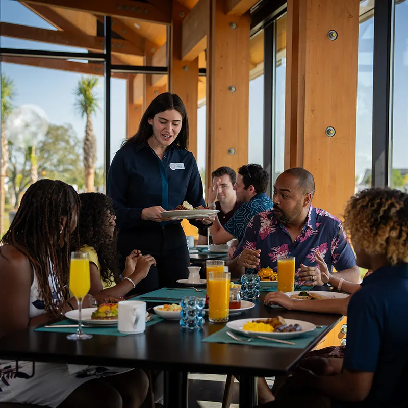 Family Eating Breakfast in Twin View An image of a family enjoying time together while being served breakfast in Twin View Restaurant and Bar at Evermore Orlando Resort.