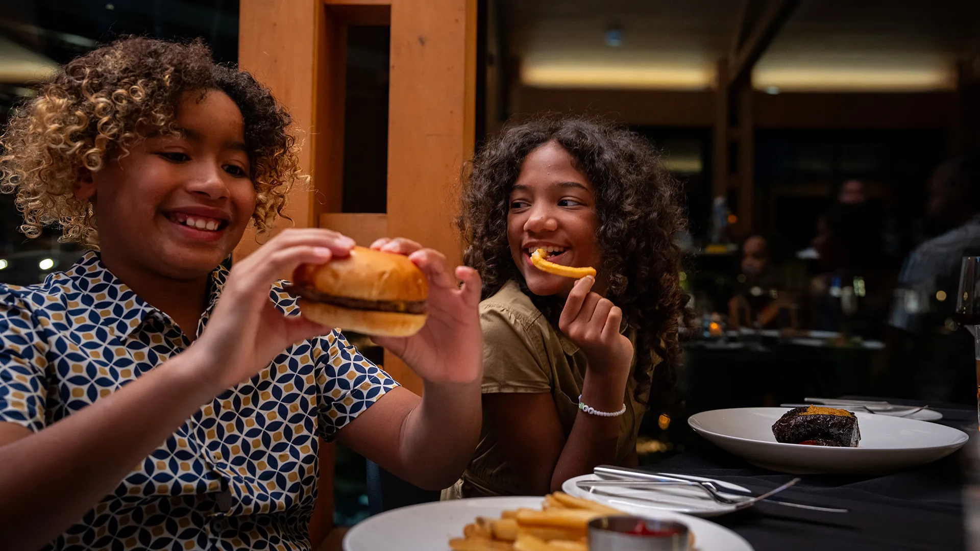 Kids Eating in Twin View An image of two kids smiling and enjoying their food while eating dinner in Twin View Restaurant and Bar at Evermore Orlando Resort.