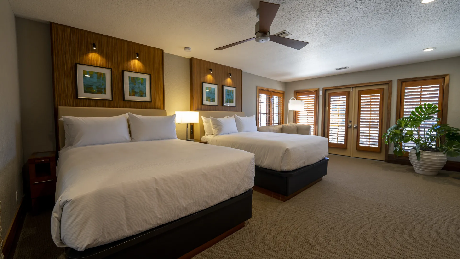 Villa double queen bedroom An image of an Evermore Orlando Resort Villa bedroom featuring 2 comfortable queen-sized beds inside of a large bedroom and a set of double doors leading out to an exterior patio.